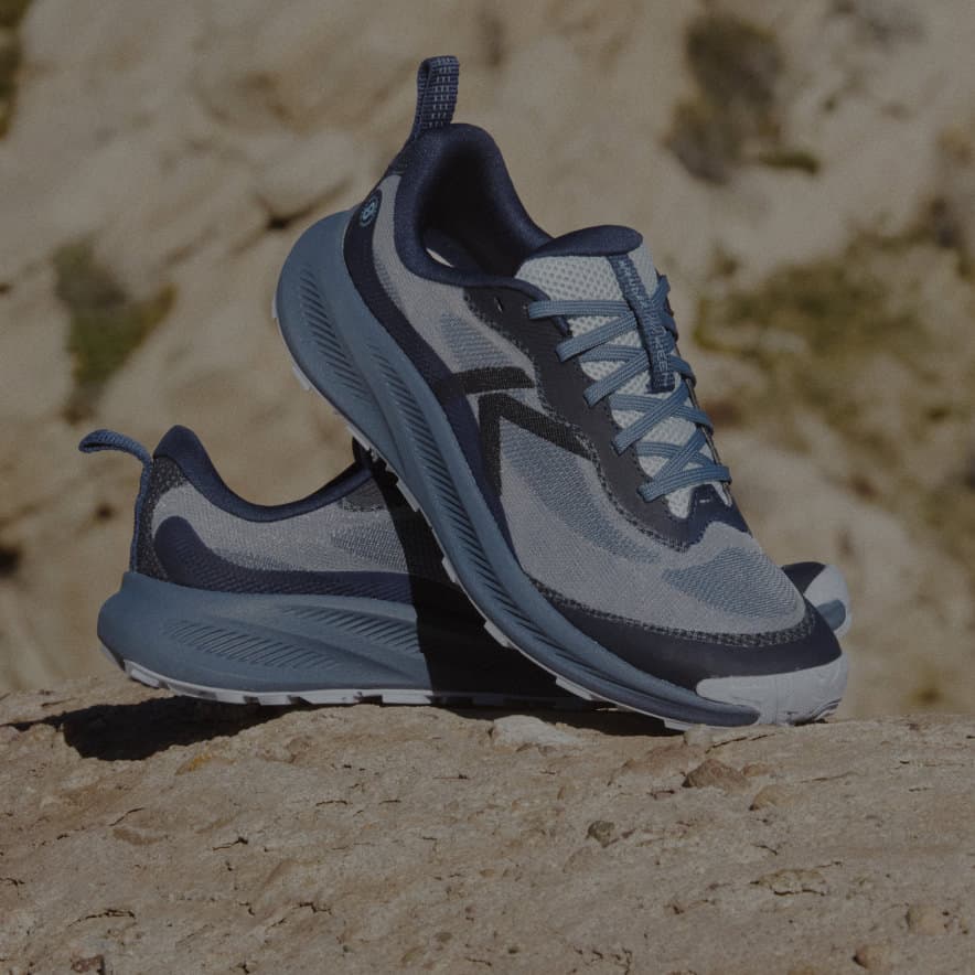 A pair of Navy blue Wander trail running shoes propped up on each other in a desert setting.